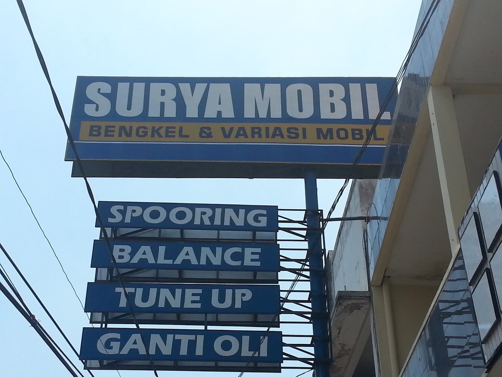 Papan nama Surya Mobil dengan layanan Spooring, Balance, Tune up dan ganti oli