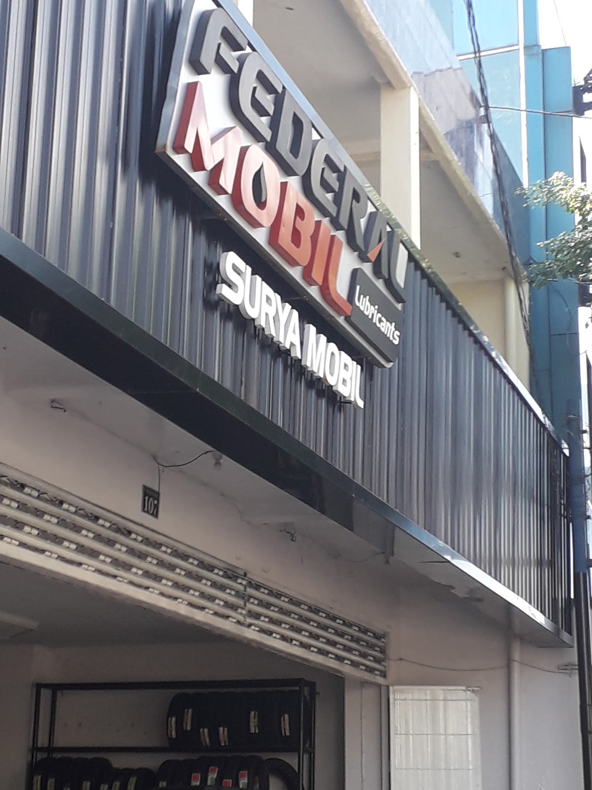 Papan nama pada fasad berwarna gelap di Surya Mobil