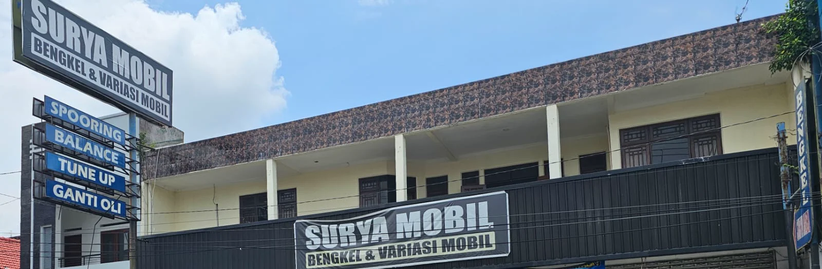 Plang Surya Mobil dan papan layanan di bagian depan bengkel